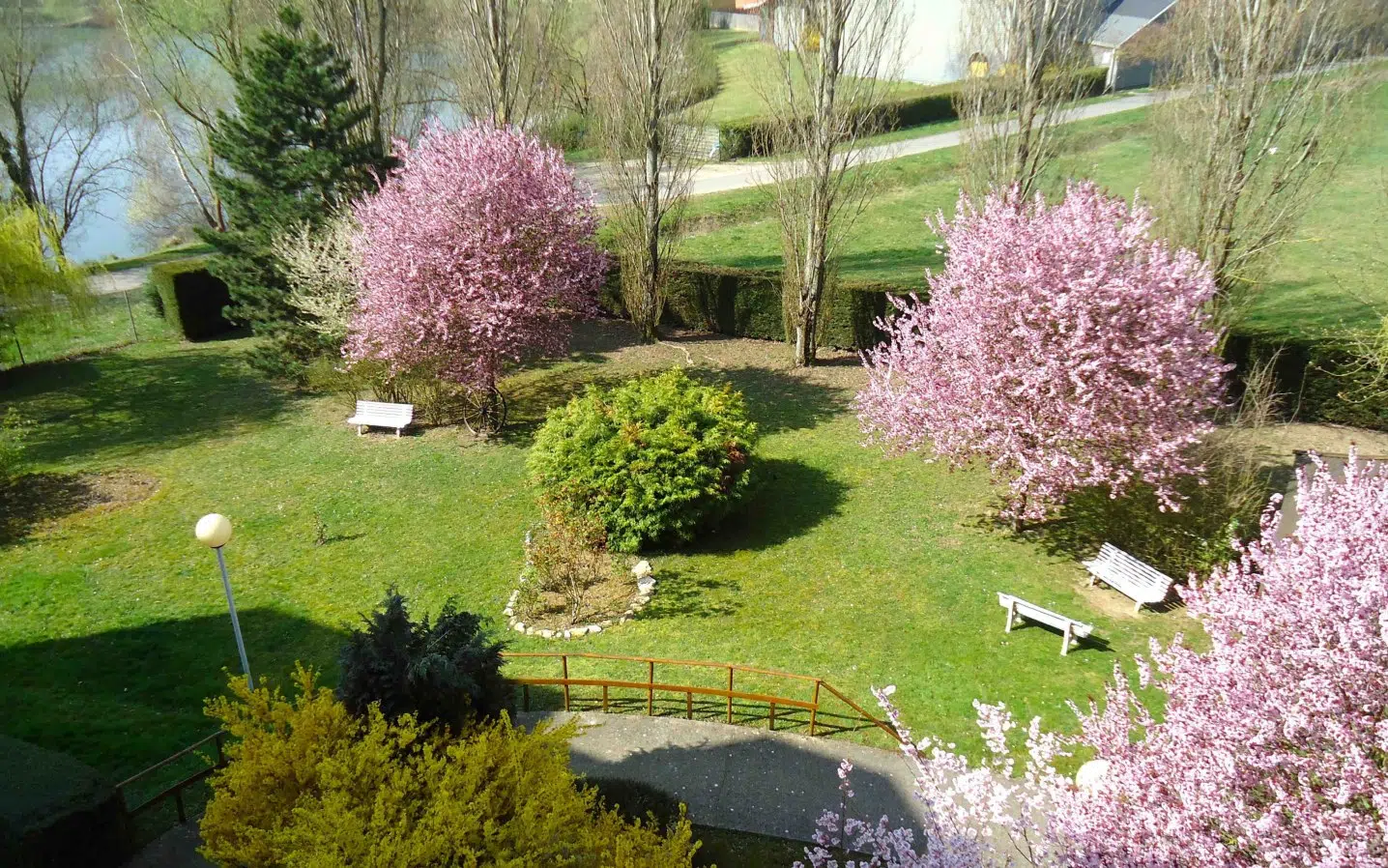Jardin fleuri et bien entretenu avec des bancs blancs - Bienvenue à l'ehpad de savigny le temps | Clinalliance Ehpad | Savigny-le-temple