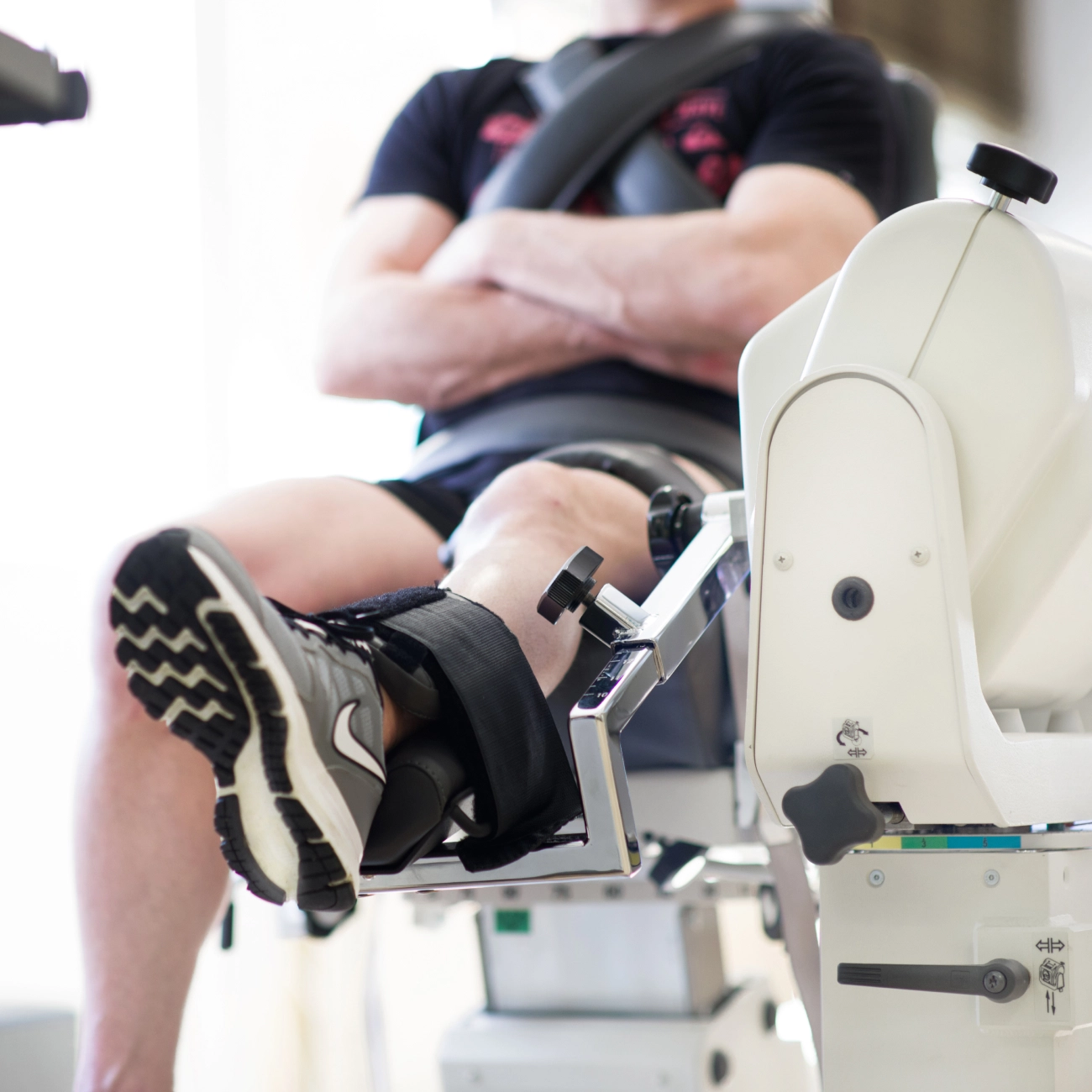 Personne assise sur un équipement de rééducation, avec une jambe allongée - une expertise | Clinalliance Villiers-sur-Orge