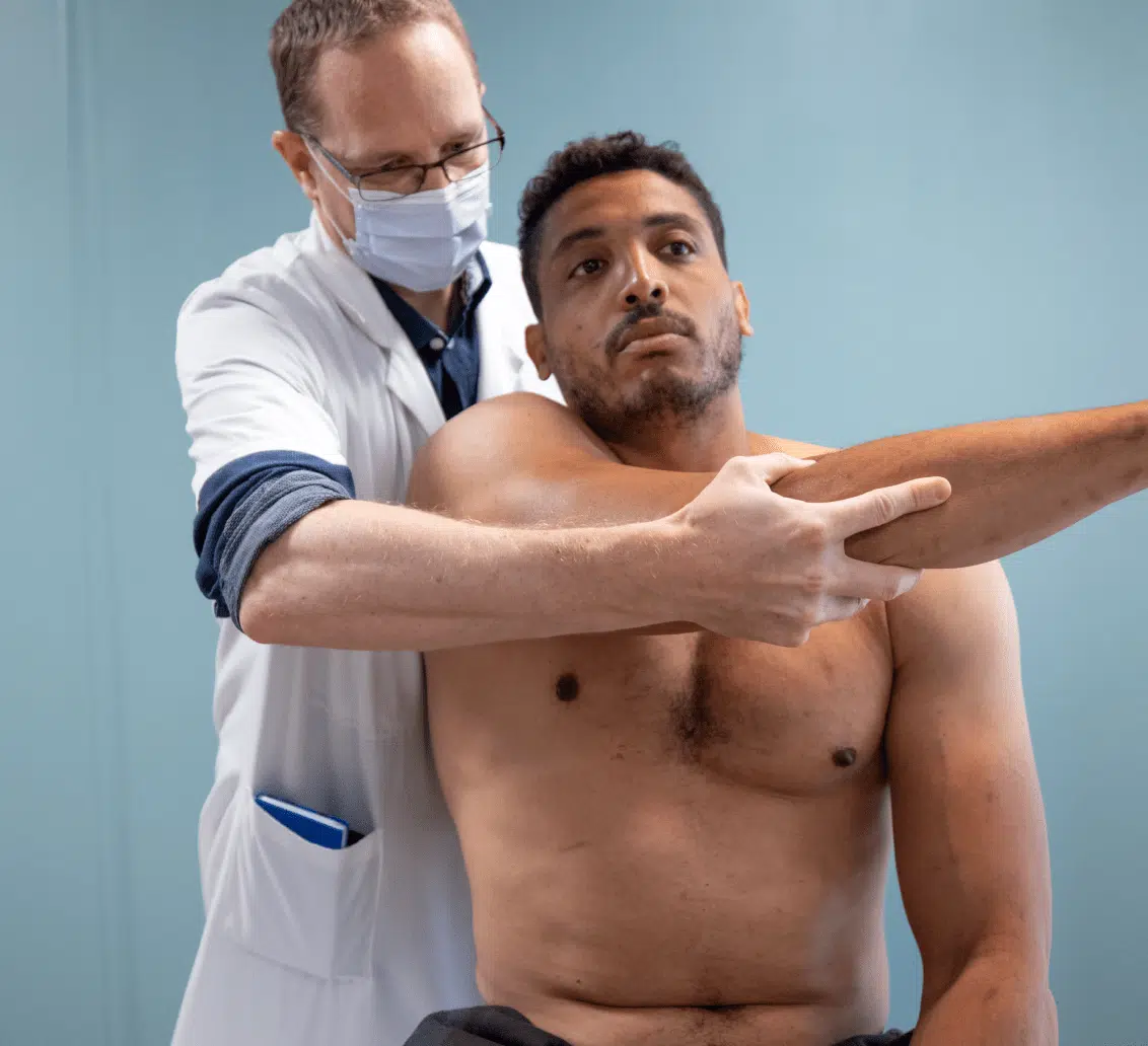 Médecin examinant l'épaule d'un patient torse nu - Prévention blessures | Clinalliancve Villiers-Sur-Orge