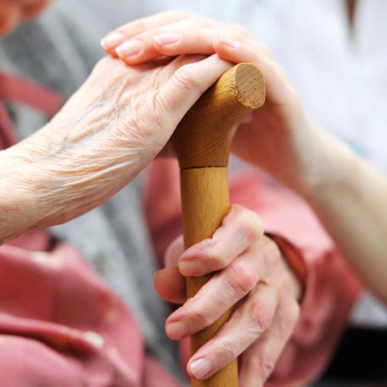 paire de mains d'une personne âgée tenant une canne en bois | Clinalliance Paris