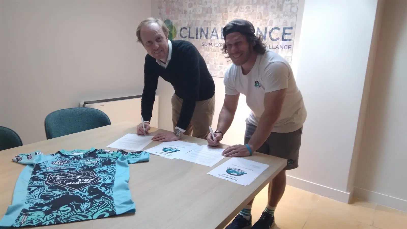 Deux personnes en train de signer des documents sur une table avec un maillot de sport | Clinalliance Paris