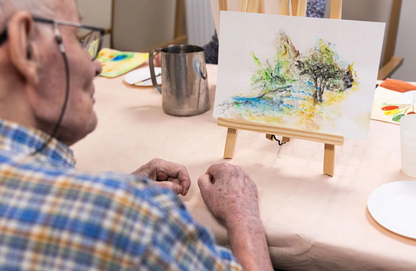 Homme âgée observant une peinture colorée sur un chevalet - activités artistiques | Clinalliance Paris