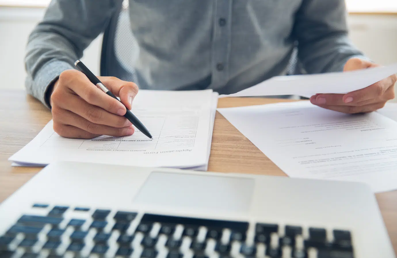 Homme assis dans un bureau tenant un stylo dans une main et un document dans l'autre - votre admission | Clinalliance Paris