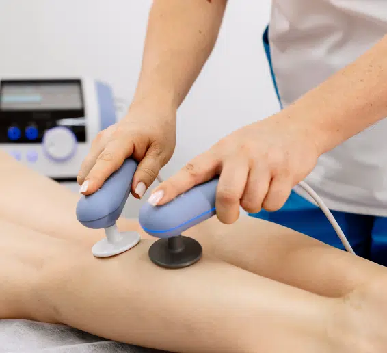Appareils à main connectés à une machine utilisés pendant une séance thérapeutique sur une jambe - tecartherapie | Clinalliance Paris