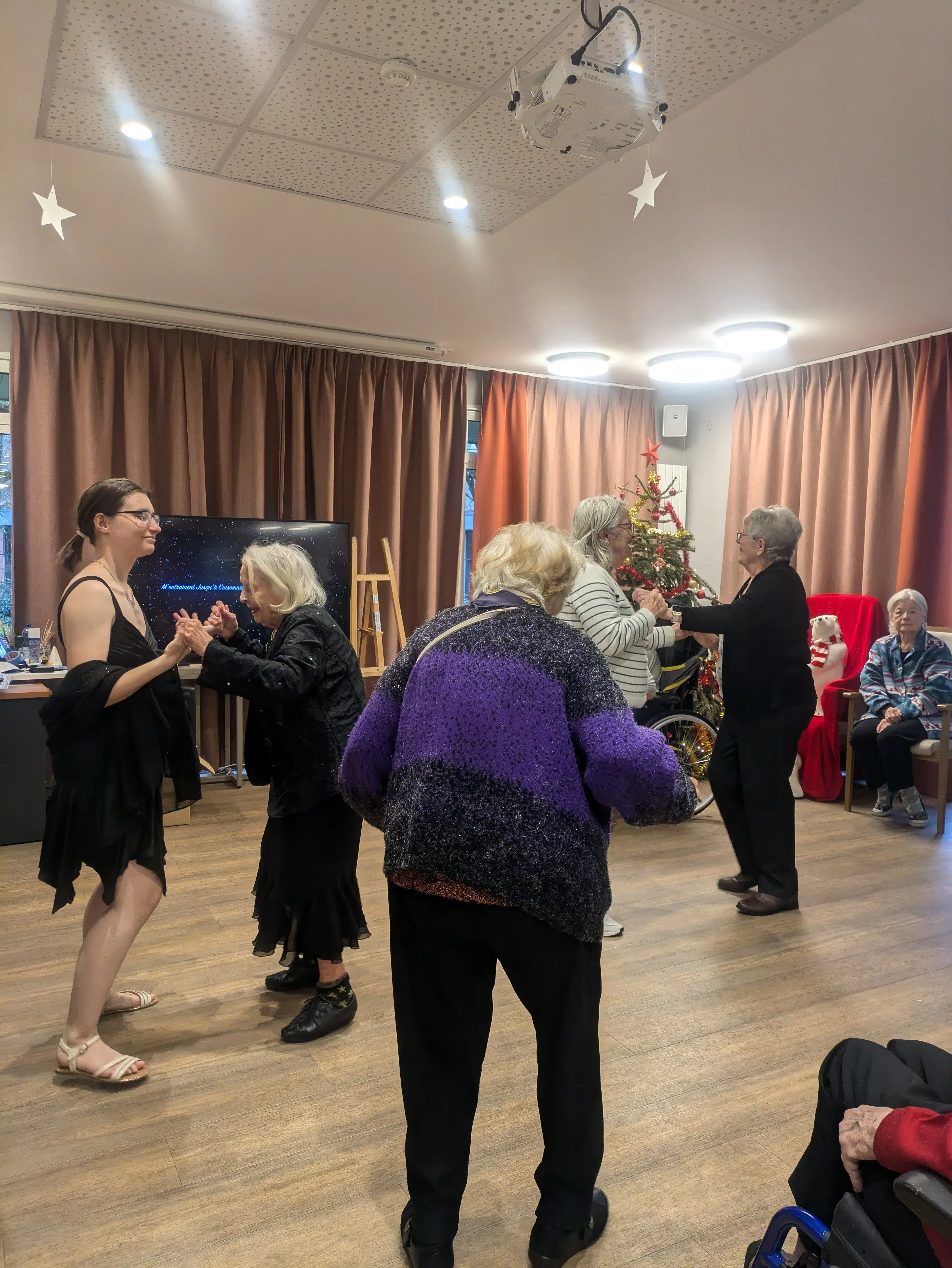 Groupe de personnes agées dansant dans une salle avec un sapin de Noël | Clinalliance | Maurepas
